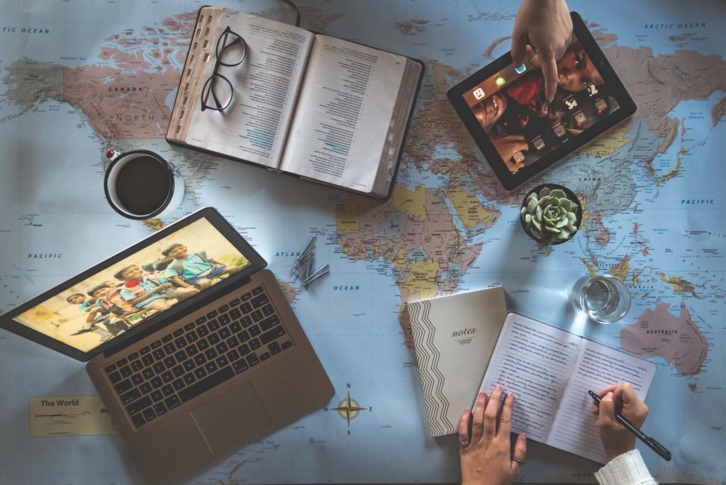 A computer bible and notebook on top of a map